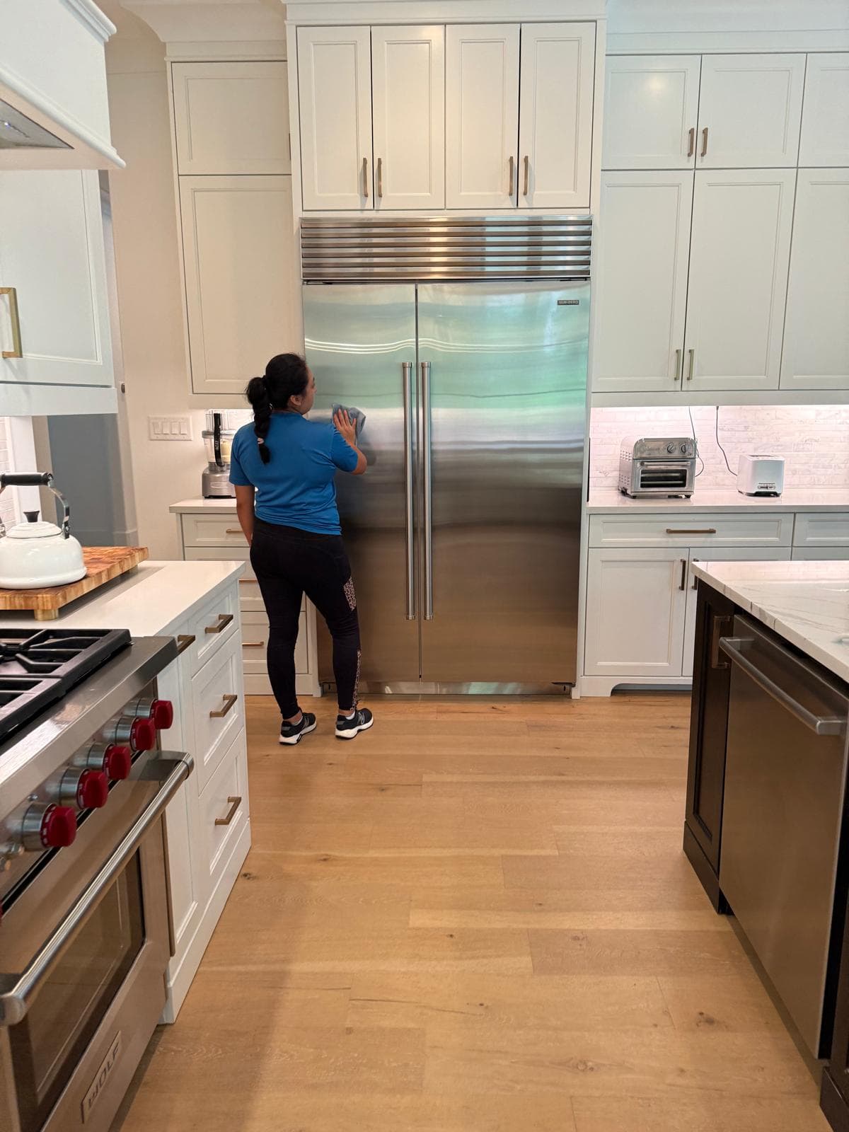 Stainless steel refrigerator being wiped during a professional clean