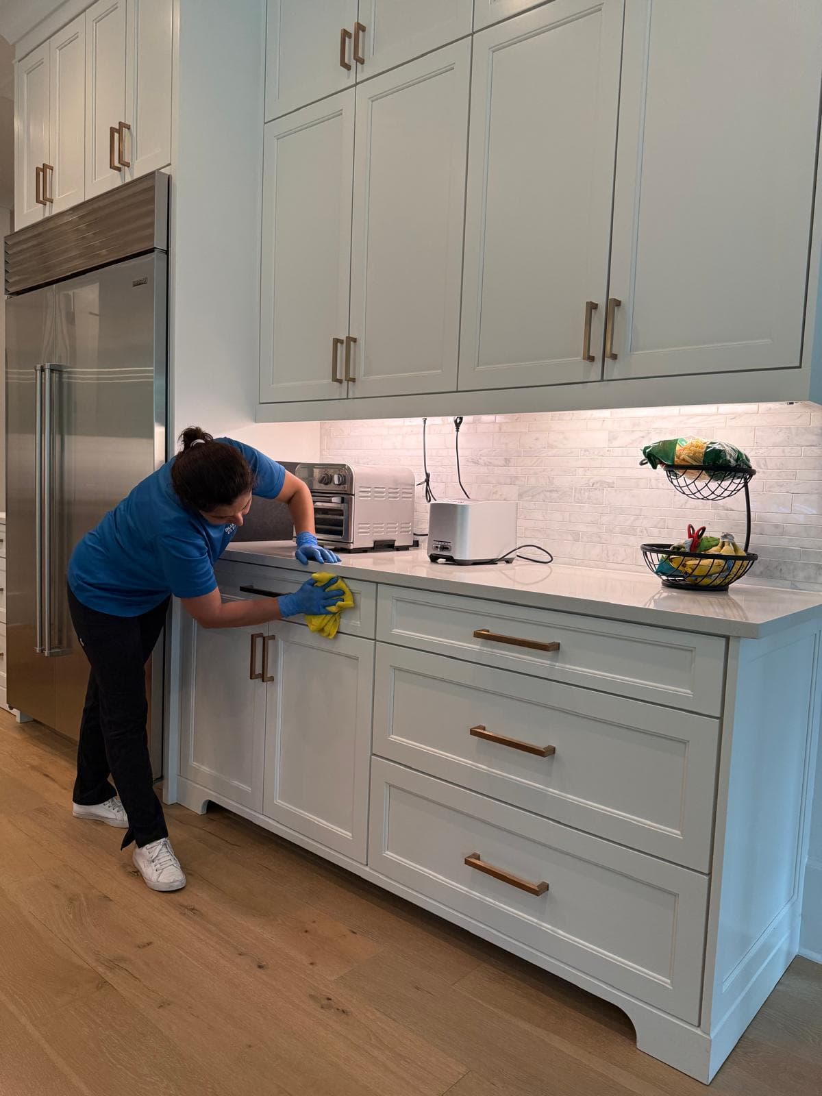 Team member wiping kitchen cabinet fronts