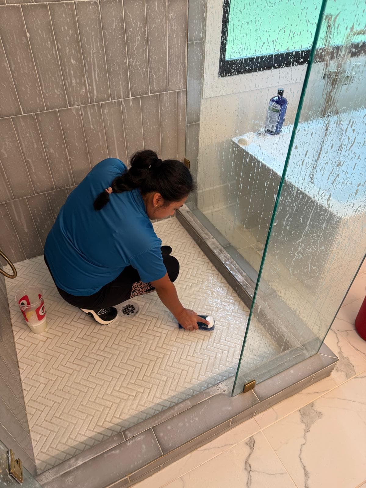 Team member scrubbing a herringbone tile shower floor